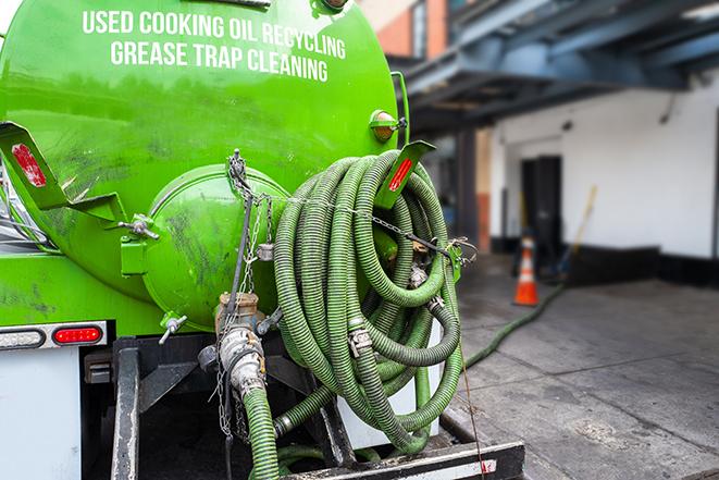 a professional plumber using a pump to empty a grease trap in Hacienda Heights, CA